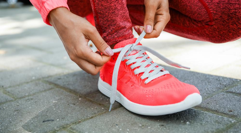 Woman lacing up walking shoes outdoors before walk