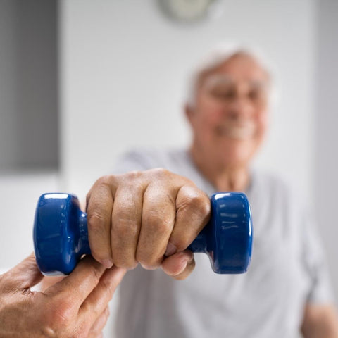 Old man exercising with dumbbell while being assisted