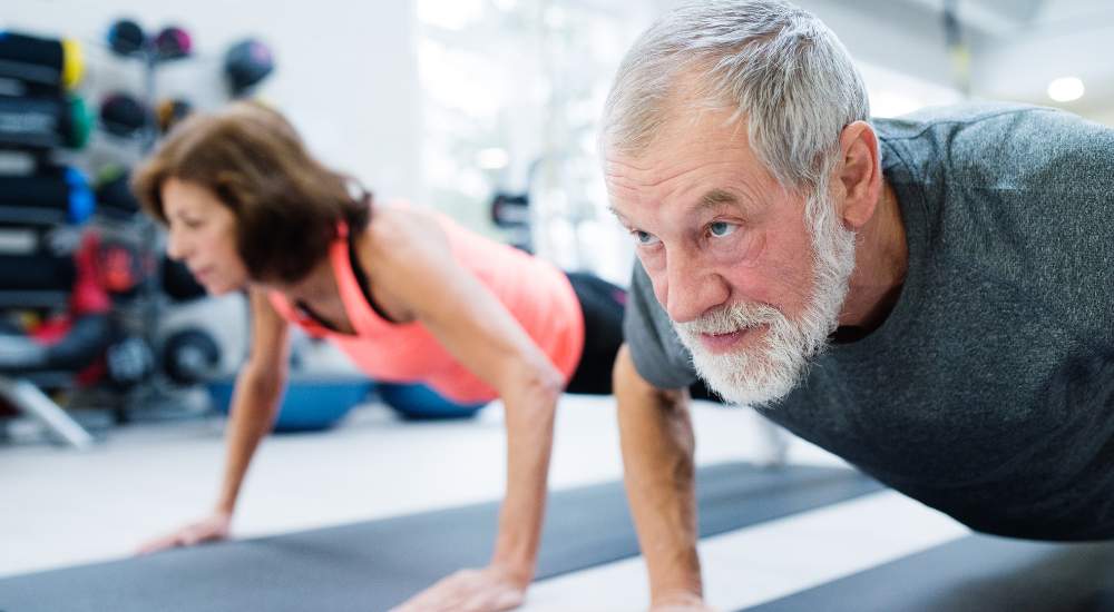 Senior couple doing push ups at home gym