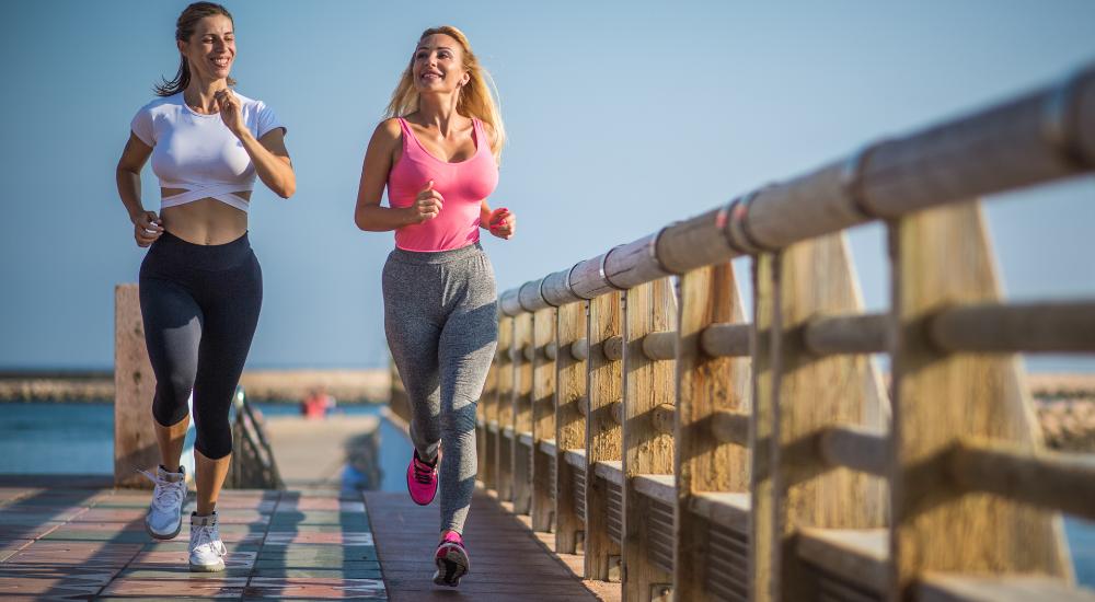 Two young atheltic women brisk walking outdoors for weight loss