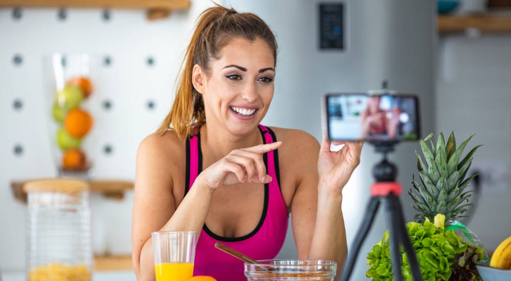 Female fitness influencer promoting health products in front of recording phone