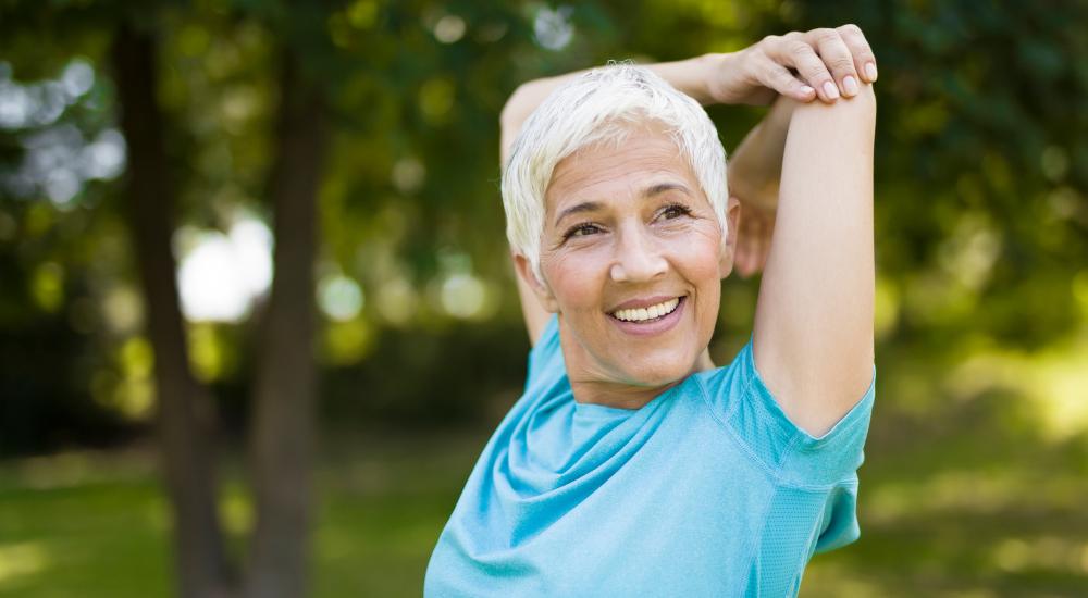 Old woman happily stretching outdoors before going on a walk