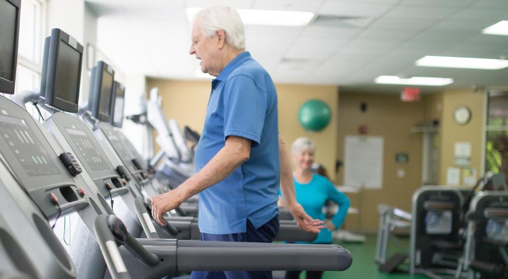 Elderly man walking on treadmill at a gym