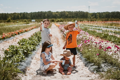 Four kids outside holding sun care products