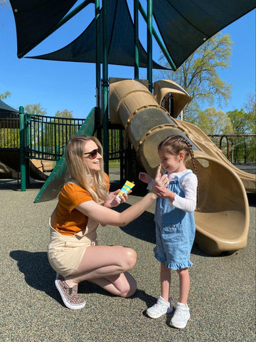Mom applying sunscreen on daughter at the park
