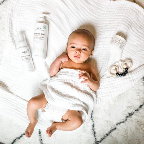 Baby laying next to Babo Botanical baby hair products