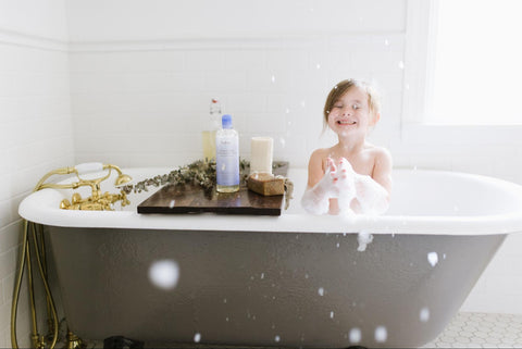 Kid taking a bath with all the bath essentials