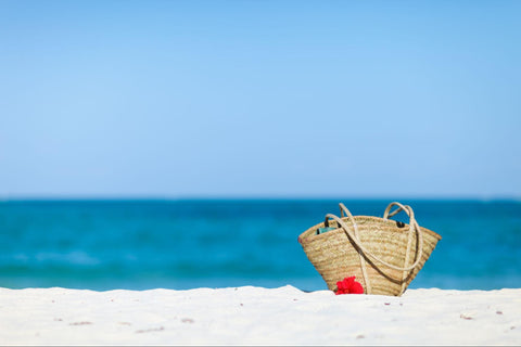 Bag on beach filled with beach packing list essentials