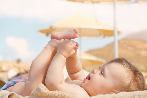 Baby at beach holding his legs in the air