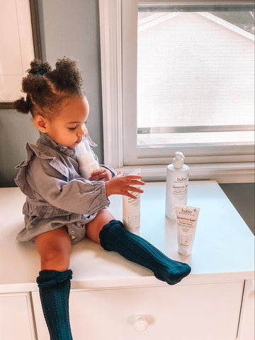 Child sitting on counter with Babo Botanicals skin care products that contain coconut oil