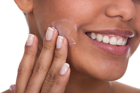 Woman applying face cream for dewy skin