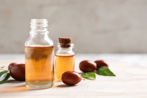 jojoba oil in a bottle with seeds next to it