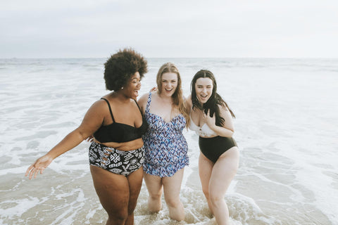 Three friends at the beach in bathing suits