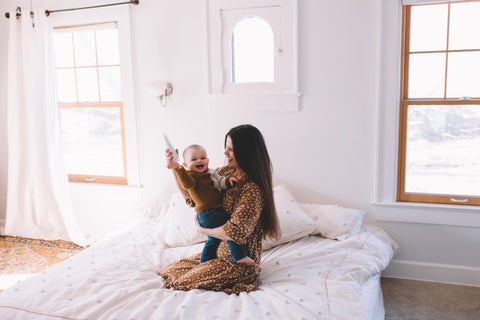 Woman holding baby on bed