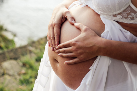 woman holding pregnant belly with stretch marks 