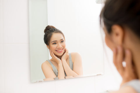 Woman smiling while looking at her face in the mirror