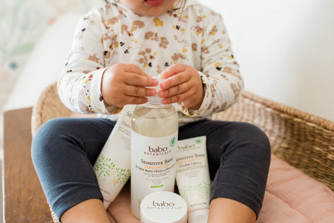 toddler sitting with Babo Sensitive Baby products