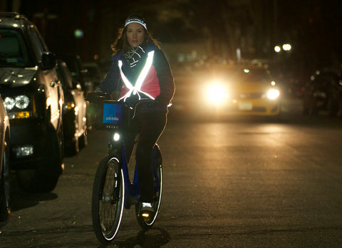 woman riding a bicycle at night wearing a vespert reflective vest reflective hat reflective shoelaces