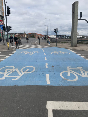 Bold blue two-way bike lane painted on the street in Copenhagen Denmark with white bicycles 