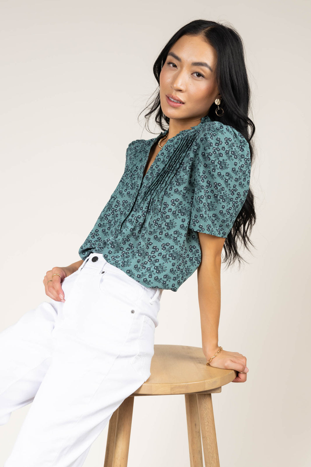 Model wearing teal floral blouse paired with white jeans