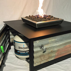 Picture of a standard propane tank on its tank holder just inside the access door of a square shaped IMPACT Fire Table