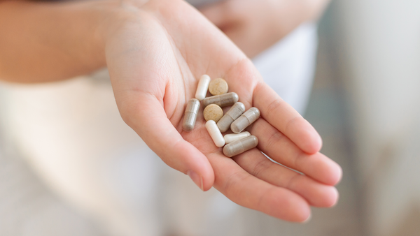 Probiotics are one kind of supplement that is useful for stress and mood - photo of woman's open hand holding several different kinds of capsules and tablets