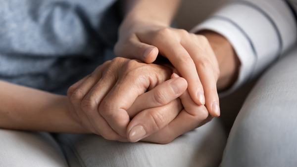 The clasped hands of two seated people