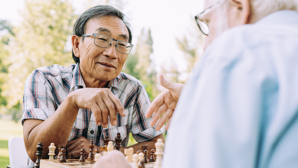 Two elderly men playing chess outside