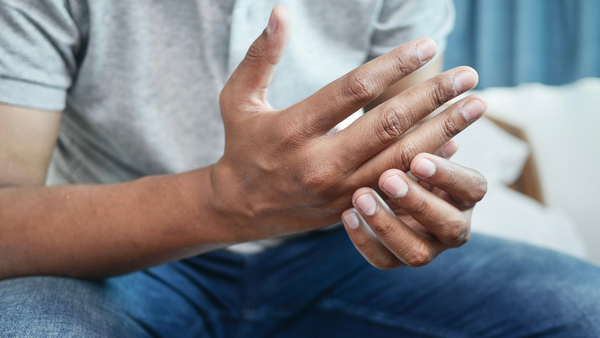 A man, seated, one hand rubbing the other, as if anxious about something