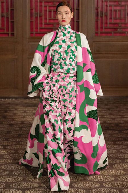 Valentino Fall 2020 fashion show image showing model in pink, green and white pantsuit with long flowing jacket
