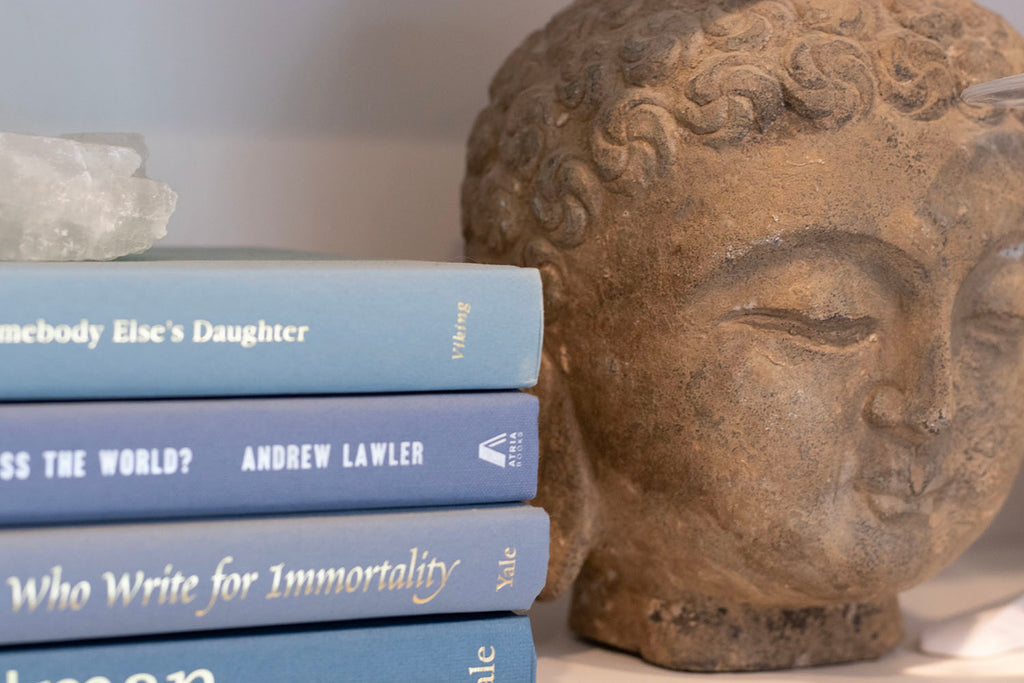 bookshelf styled with buddah next to blue books with quartz on top 