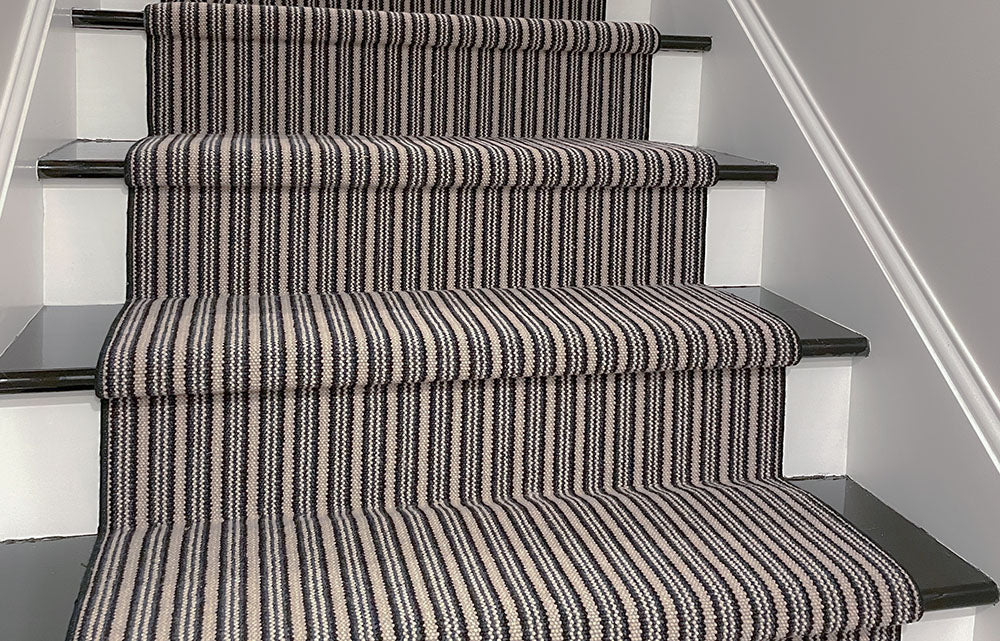 white stairs with black treads and striped blue and black carpet runner
