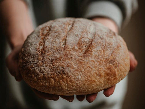 close up of woman's hands holding loaf of homemade bread