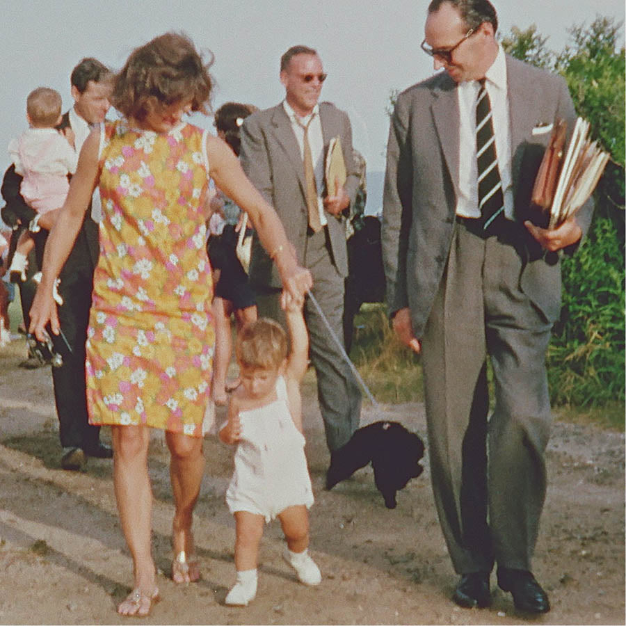 Jackie Kennedy wearing a printed dress walking on sandy path in Hyannisport