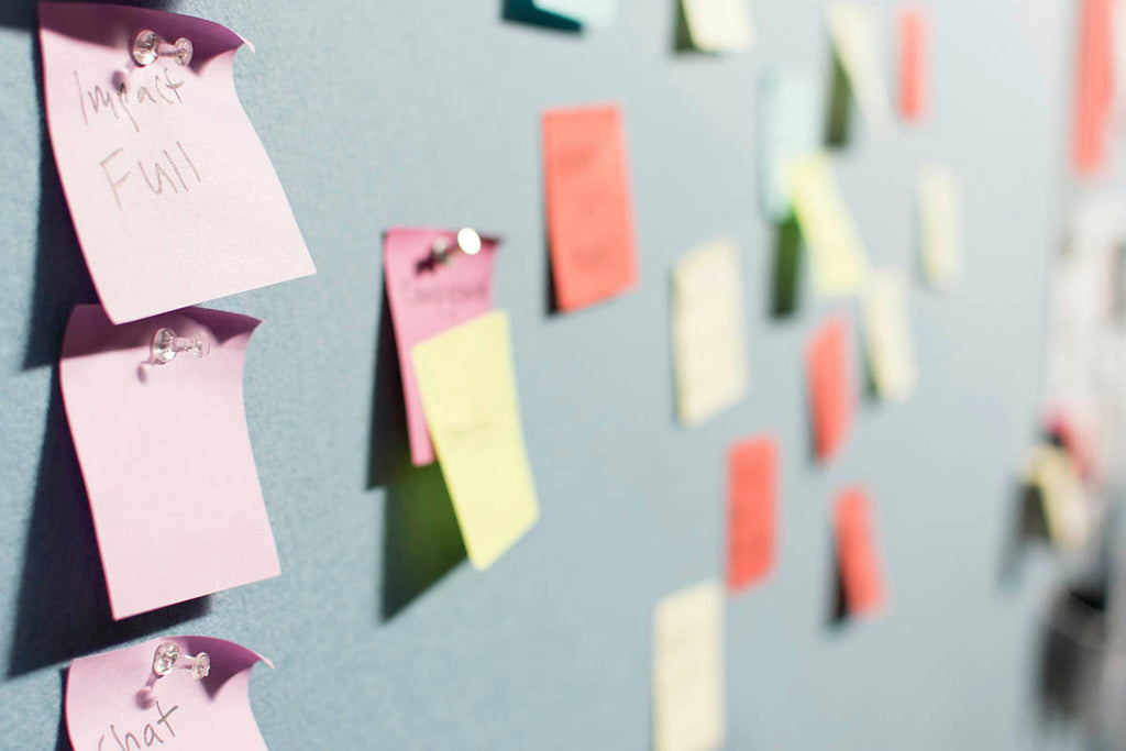 gray board with multi colored post it notes. 