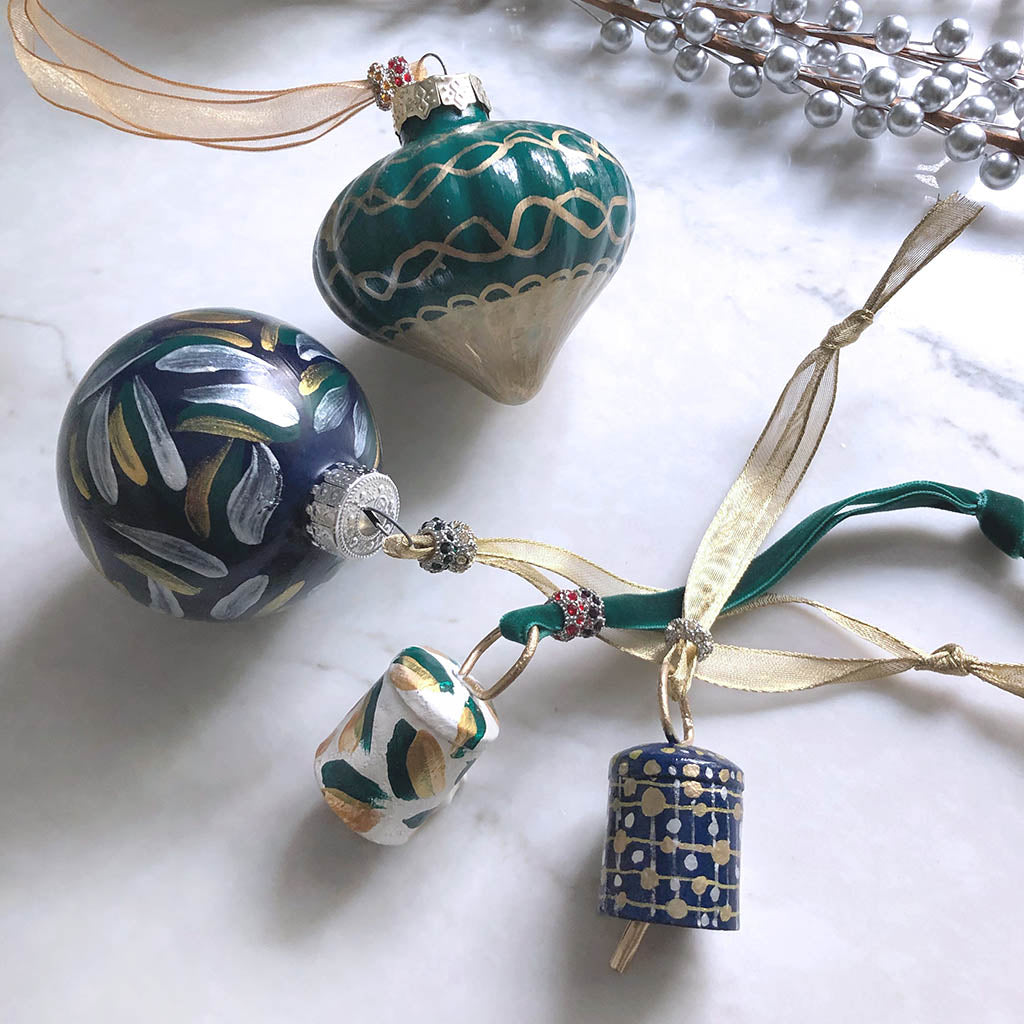 hand-painted Christmas ornaments in green, blue, white, and gold with abstract patterns