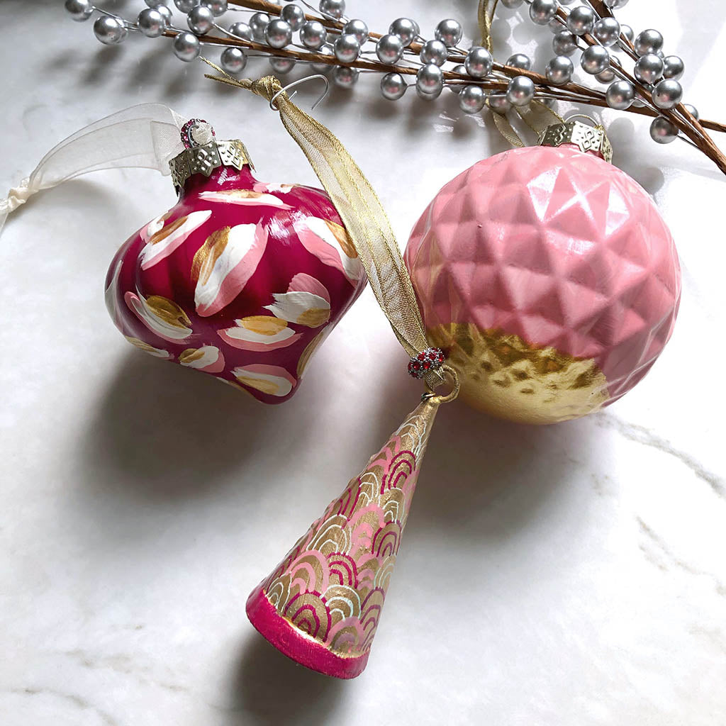 hand-painted Christmas ornaments in maroon, white, pink, and gold. Patterns are abstract.