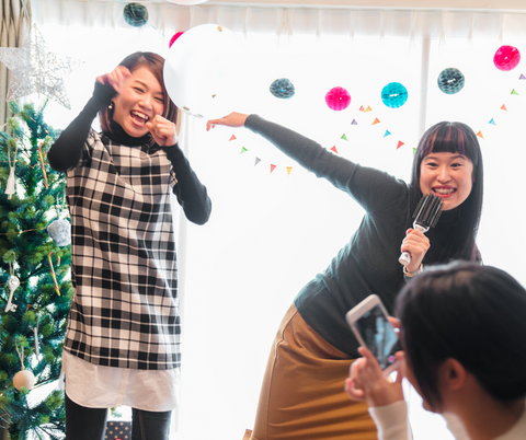Women taking photos, dancing and singing karaoke around the Christmas tree.