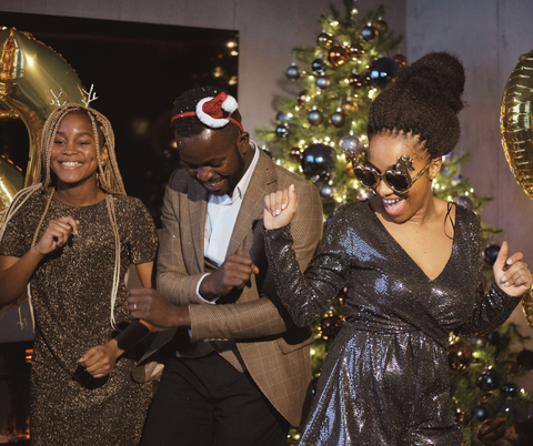 Three friends dressed up and dancing at a christmas house party.