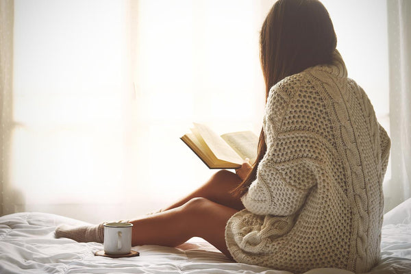 a girl sitting in bed reading a book fill warm candle gift basket friend relax gift basket stress determine house rest benefit