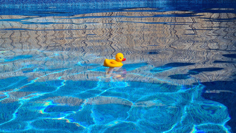 A rubber ducky floating in a backyard pool on fourth of july.