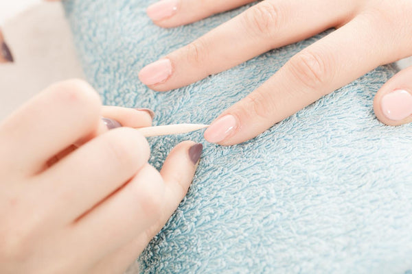 someone pushing back their cuticles apply cuticle oil soak removal method light release warm soapy water nails short