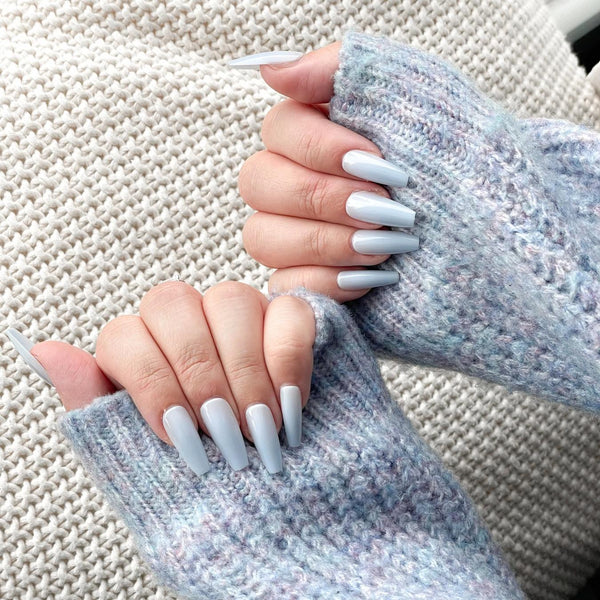 someone wearing a baby blue sweater with blue nail polish short nails transitional period nail lacquer absolutely love red nails nail color
