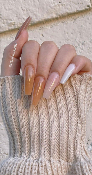 someone's hand wearing a sweater with long translucent stiletto nails home decor pop gold pink gold pumpkins white pumpkins thanksgiving color scheme orange