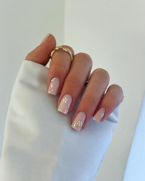 someone's hand with nude nail polish and white flowers nail design nail designs nail design abstract design manicure fun nude