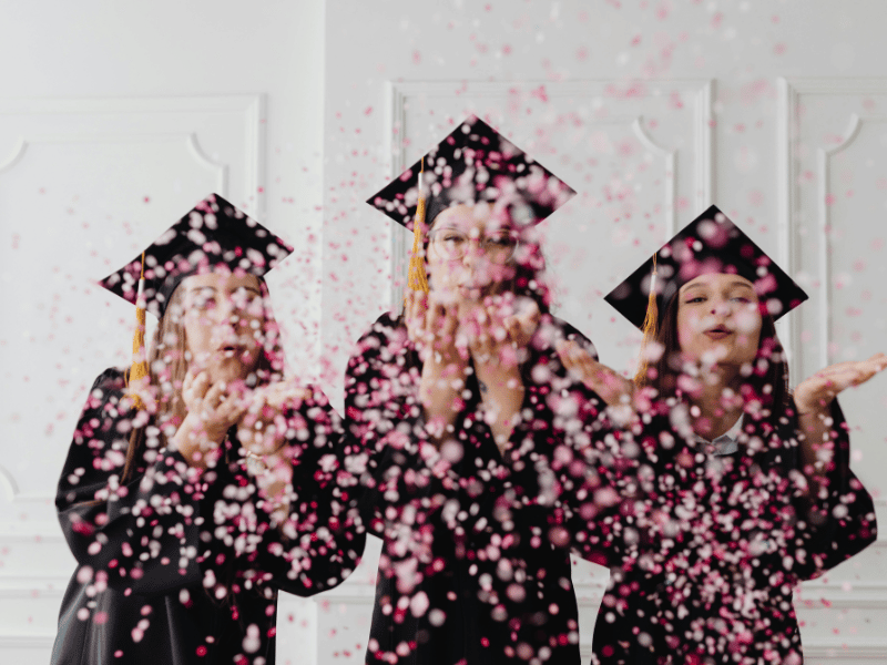 women celebrating graduation together with confetti