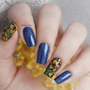 A manicured hand in blue with floral designs in a combination of yellow and green.