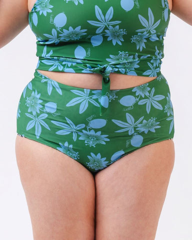 Photo of a woman wearing a green and blue floral/ white and black floral reversible swim bottom (green and blue floral side) and a green and blue floral swim crop top