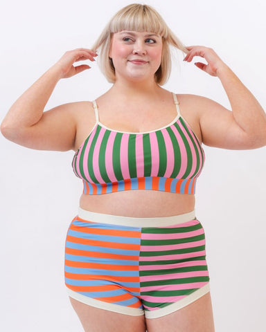 Photo of a woman wearing a multi-colored striped retro swim short bottom and a multi-colored striped swim bralette