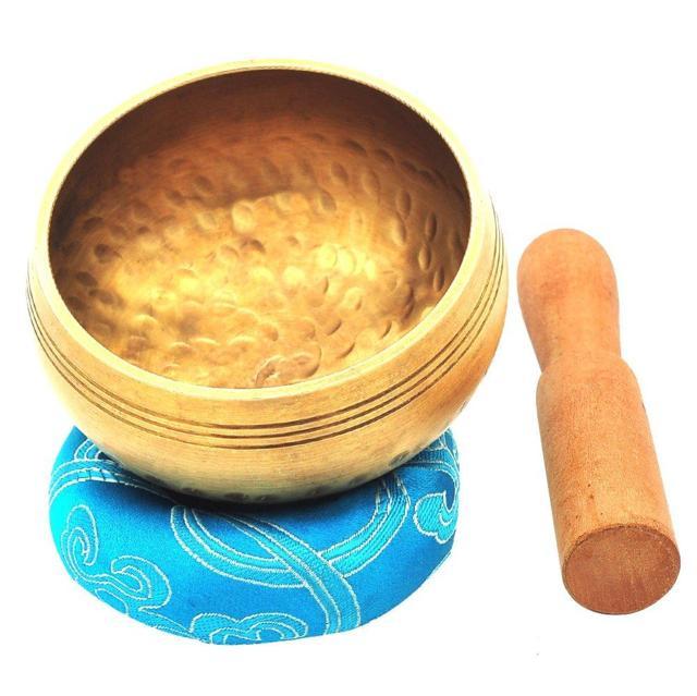 gold singing bowl with design pattern placed on a blue pillow